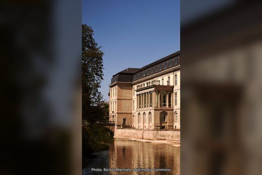 A classical building with a symmetrical facade, large windows, and a reflection in the water. 4