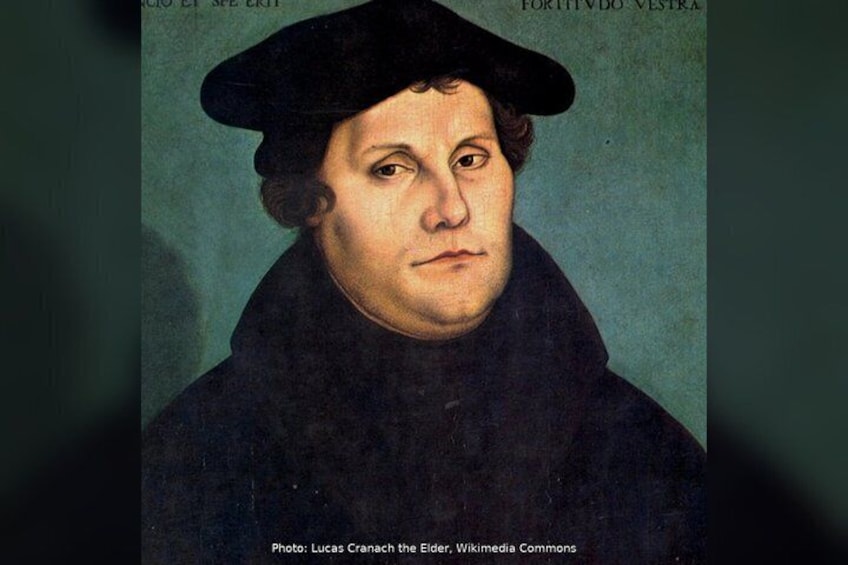 A portrait of a person wearing a dark coat and a black hat, with a plain background. 4