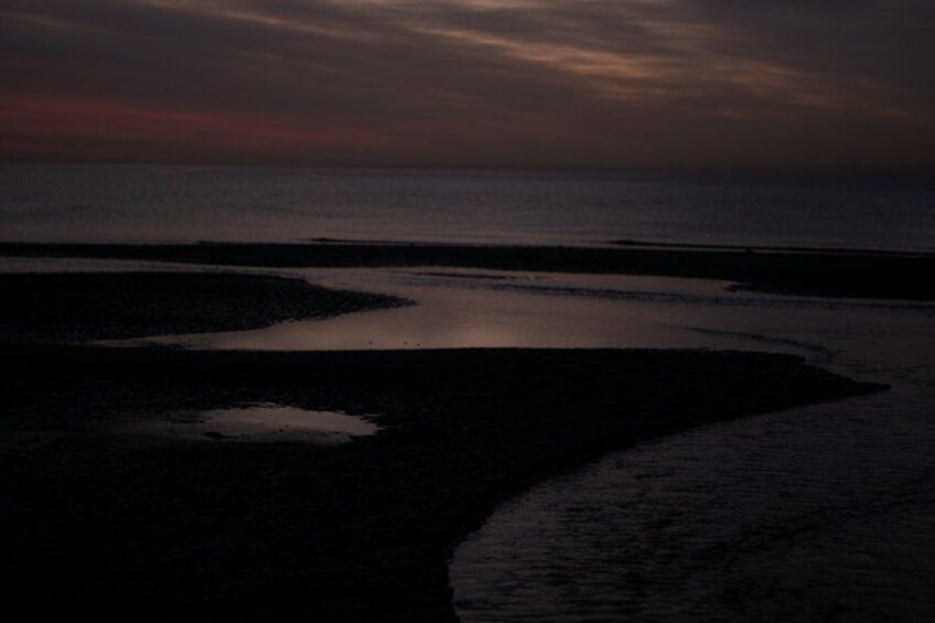 A beach at sunset with water reflecting the sky. 4