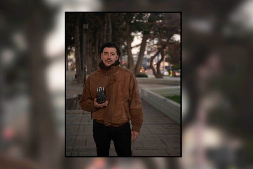 A person standing on a sidewalk holding a camera. 5