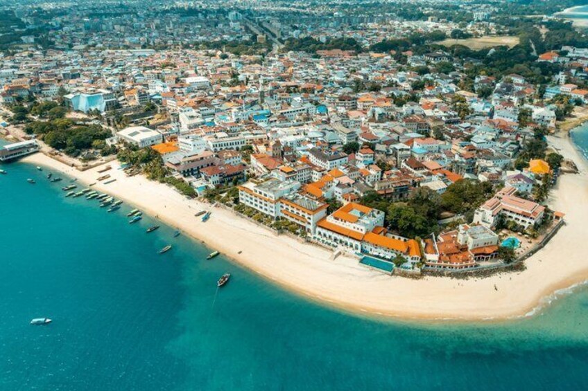 An aerial view of a coastal town with a beach, buildings, and boats. 3
