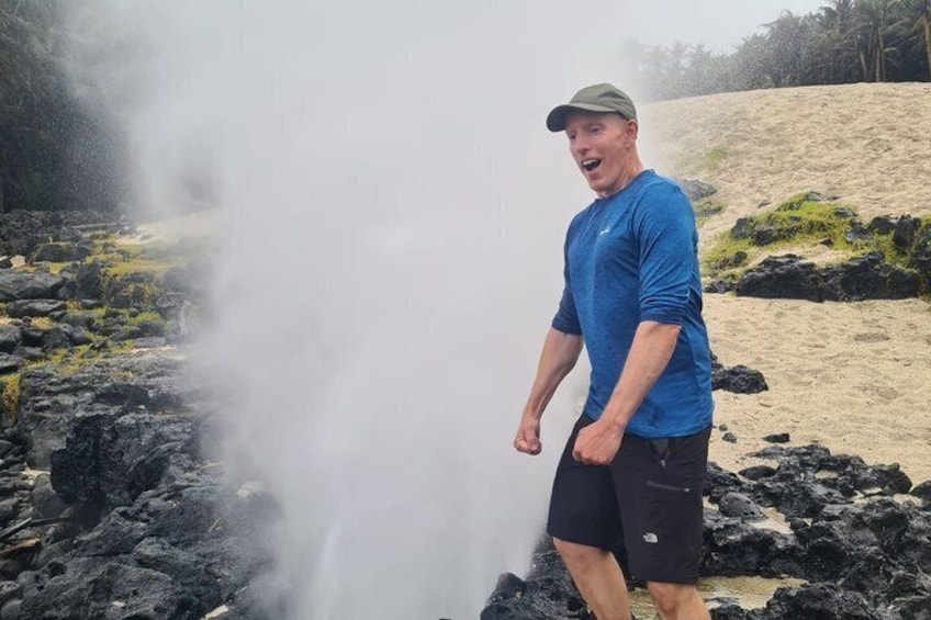 A person standing near a geothermal area with steam rising from the ground. 5