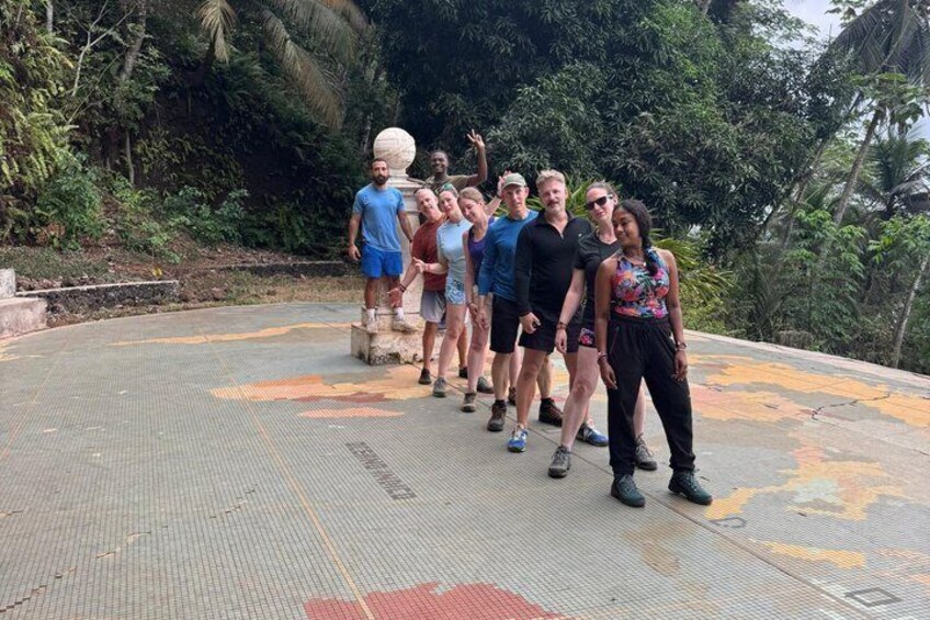 A group of people standing on a tiled platform with greenery in the background. 4