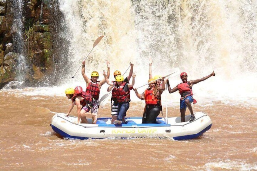 A group of people on a raft in a river with a waterfall in the background. 3