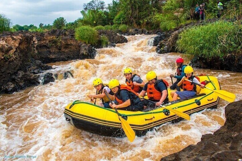 A group of people in a yellow raft navigating a river with rapids. 1