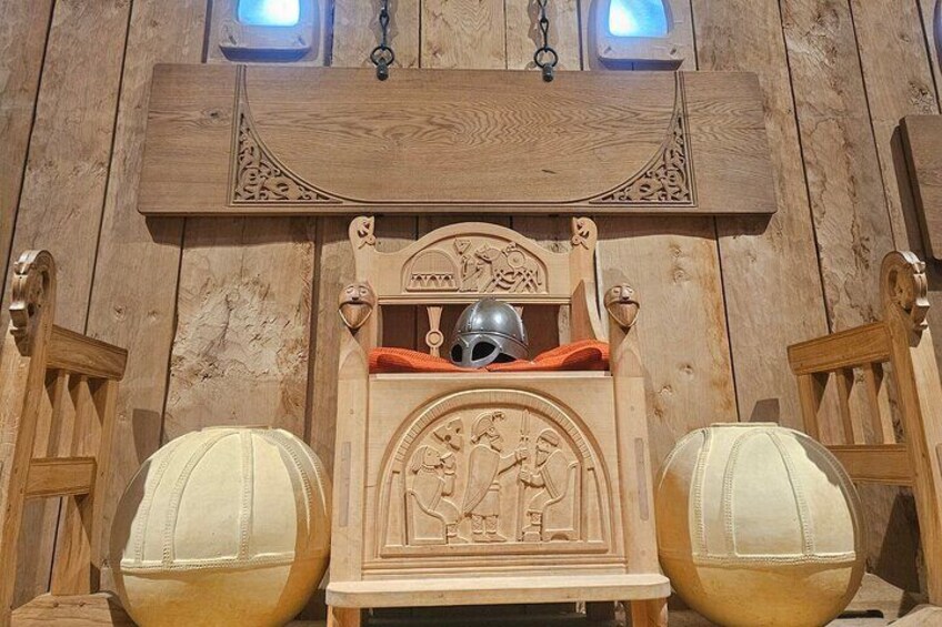 A wooden structure with carved details, two large spherical objects, and a helmet on a shelf. 5