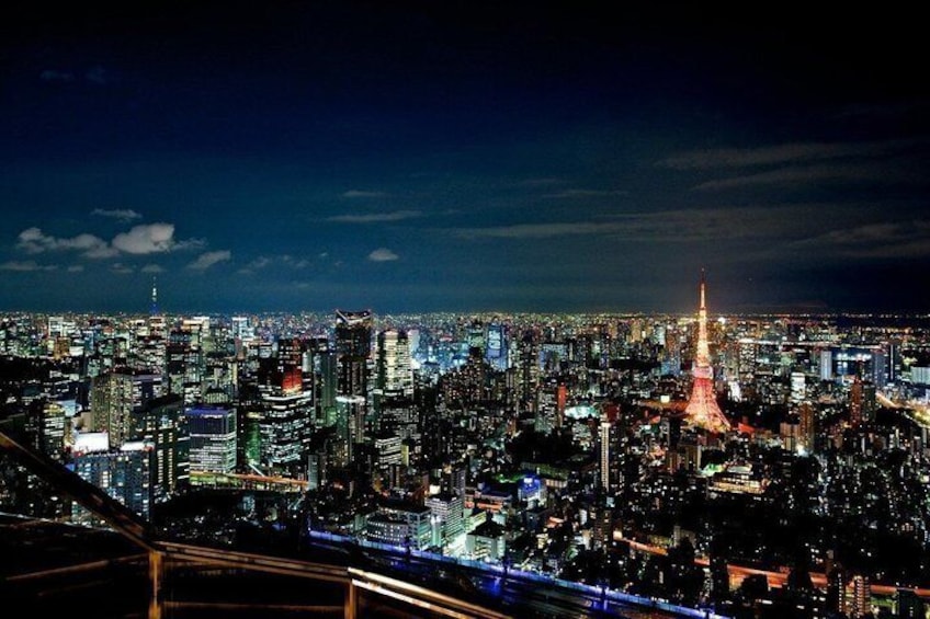A nighttime cityscape with illuminated buildings and a prominent tower. 5