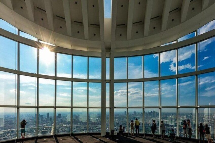 A large indoor space with a curved ceiling and large windows offering a panoramic city view. 4