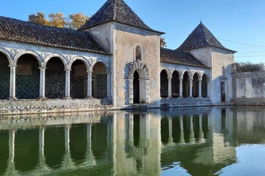 A traditional building with arched windows and a tiled roof, reflecting in a calm body of water. 5