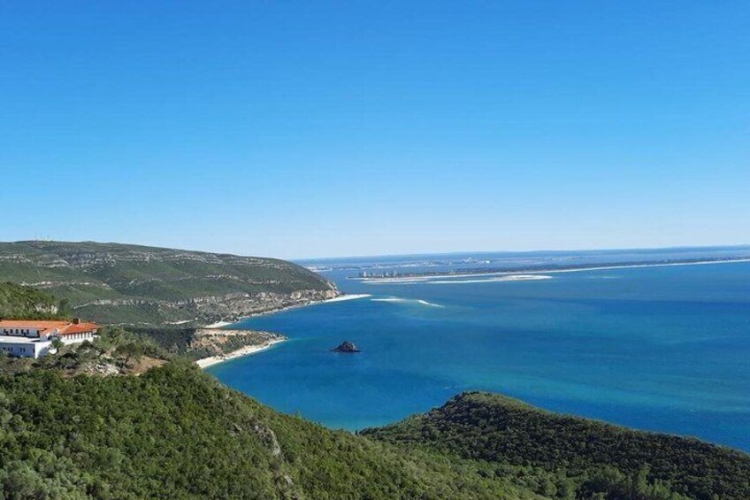 A coastal landscape with a clear blue sea, a small island, and a building on the left. 1