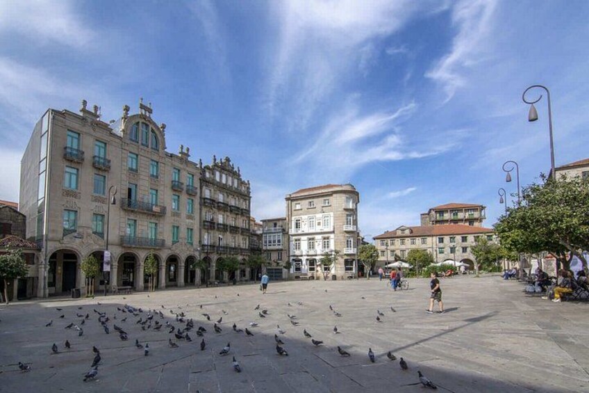A historic square with classical architecture, pigeons, and people. 5