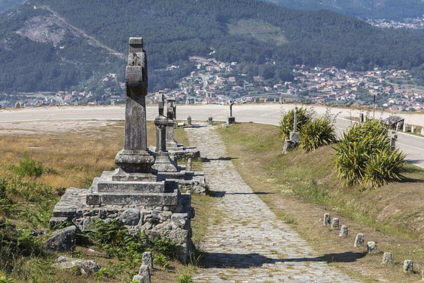 A pathway lined with ancient stone structures leading to a distant town. 2