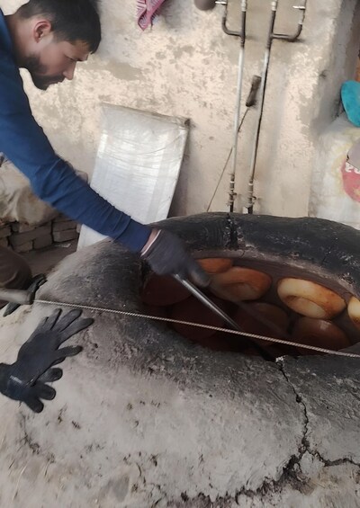 A person handling doughnuts in a large, black, round container. 5