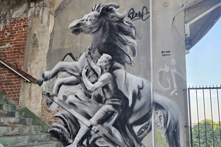 A mural of a horse with riders on a wall. 5