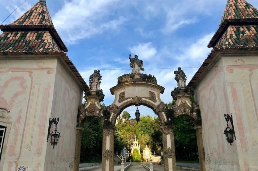 An ornate archway with statues, a tiled roof, and a building with graffiti. 2