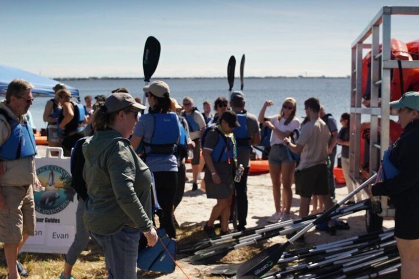 Personas en una playa con kayaks y chalecos salvavidas. 5