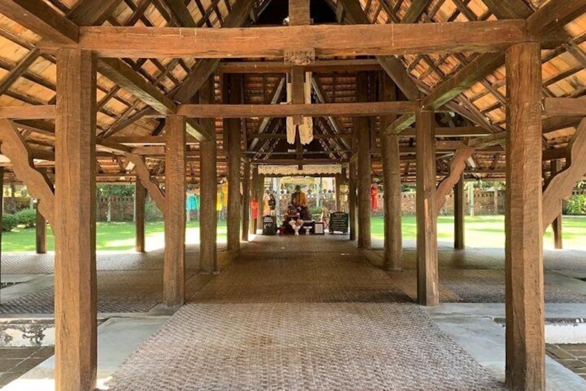 A wooden pavilion with a thatched roof, a paved floor, and a bench in the center. 3