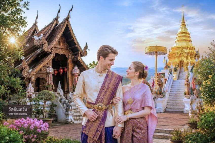 A traditional Thai temple with ornate architecture, a golden stupa, and a couple dressed in traditional attire. 1