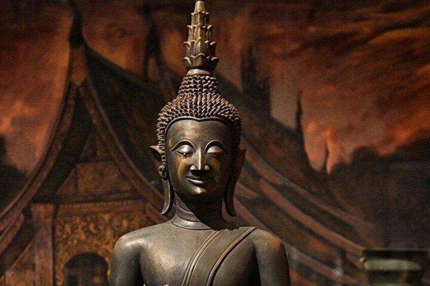 A bronze Buddha statue with intricate detailing, set against a backdrop of a traditional temple structure. 4