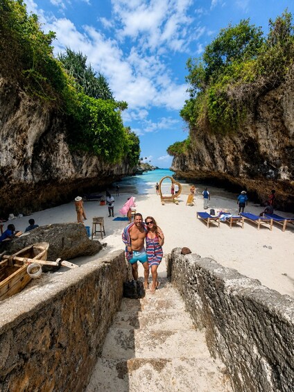 A beach with a stone staircase leading down to the water, surrounded by lush greenery and rocky cliffs. 4