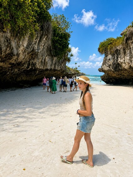 A sandy beach with people walking, a clear blue sky, and rocky cliffs. 5