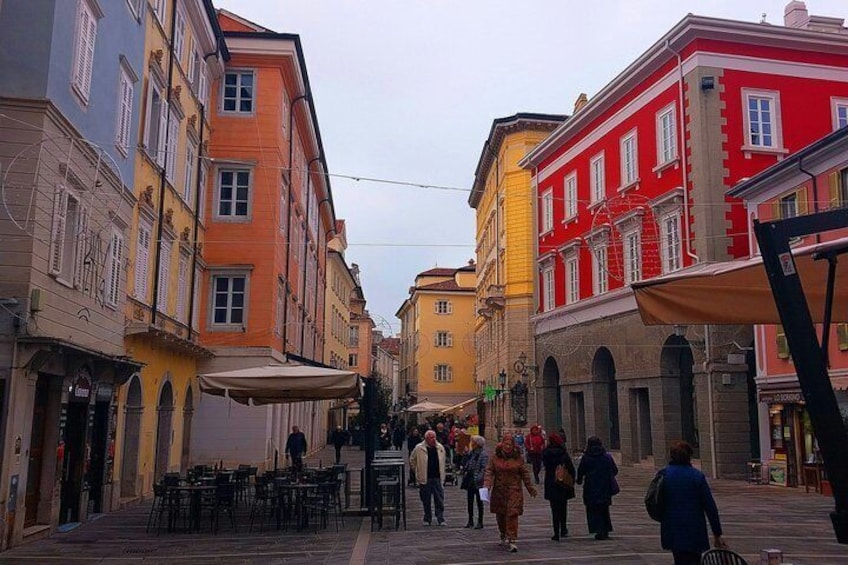 A pedestrian street lined with colorful buildings, outdoor seating, and people walking. 4