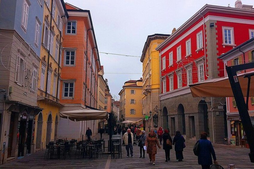 A pedestrian street lined with colorful buildings, outdoor seating, and people walking. 4