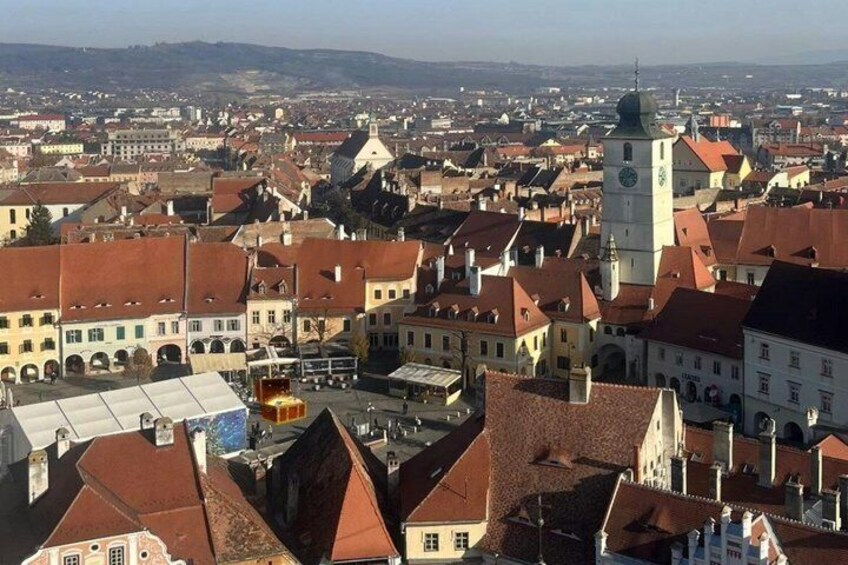 A cityscape with historic buildings, a prominent clock tower, and a river in the background. 1