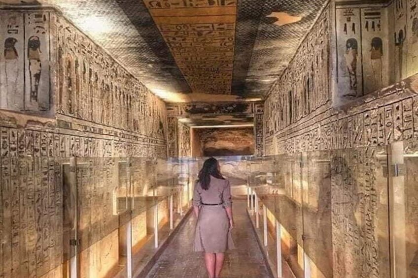 A corridor with hieroglyphs on the walls and a person walking away from the camera. 4