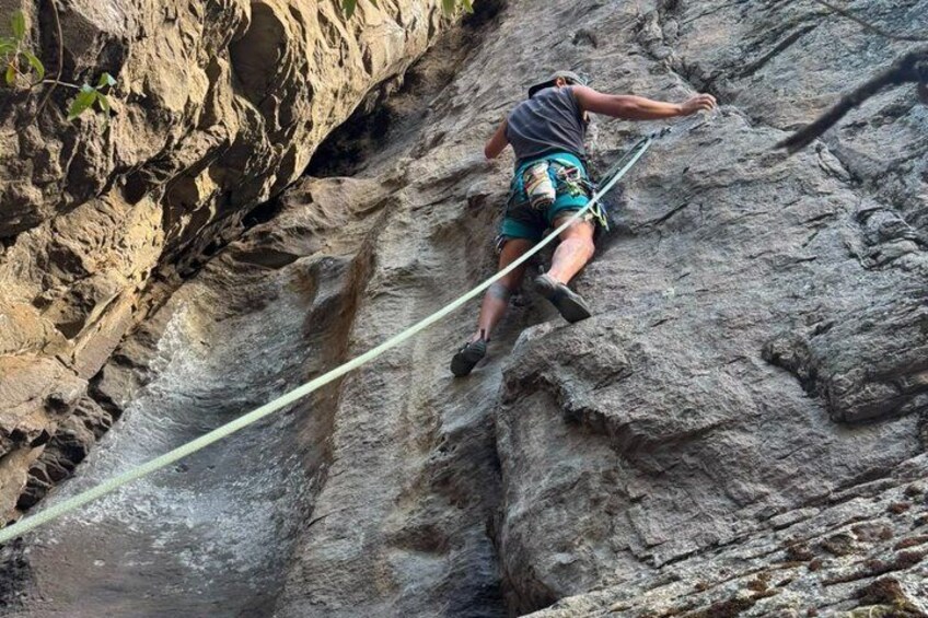 A person climbing a steep rock face using a rope for safety. 1