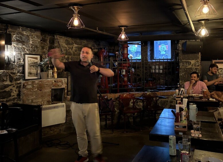 A person speaking at a bar with stone walls and hanging lights. 5