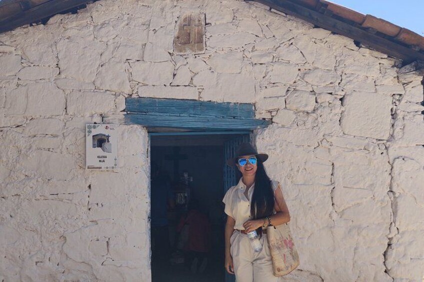 A person standing in front of a rustic stone building with a blue door. 2
