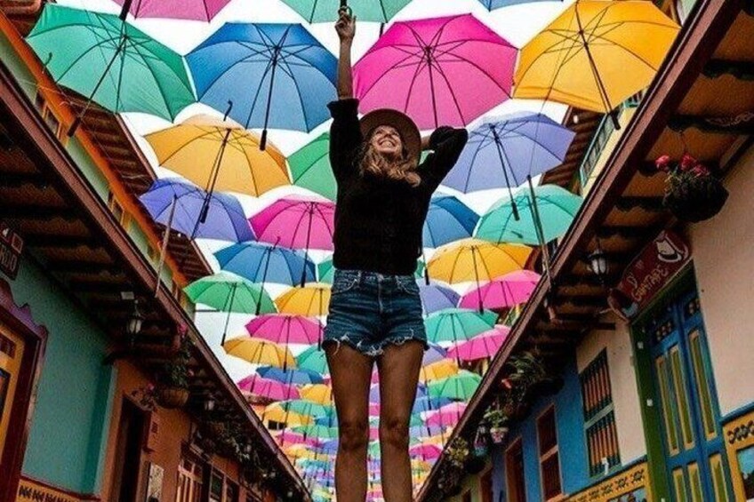 A person standing on a balcony with colorful umbrellas overhead. 4