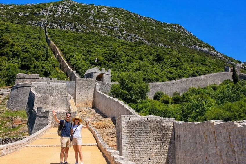 Un muro de piedra histórico con una pendiente pronunciada, cielo despejado y vegetación verde exuberante. 5