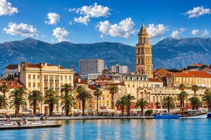 A coastal city with a prominent tower, palm trees, and a body of water. 1