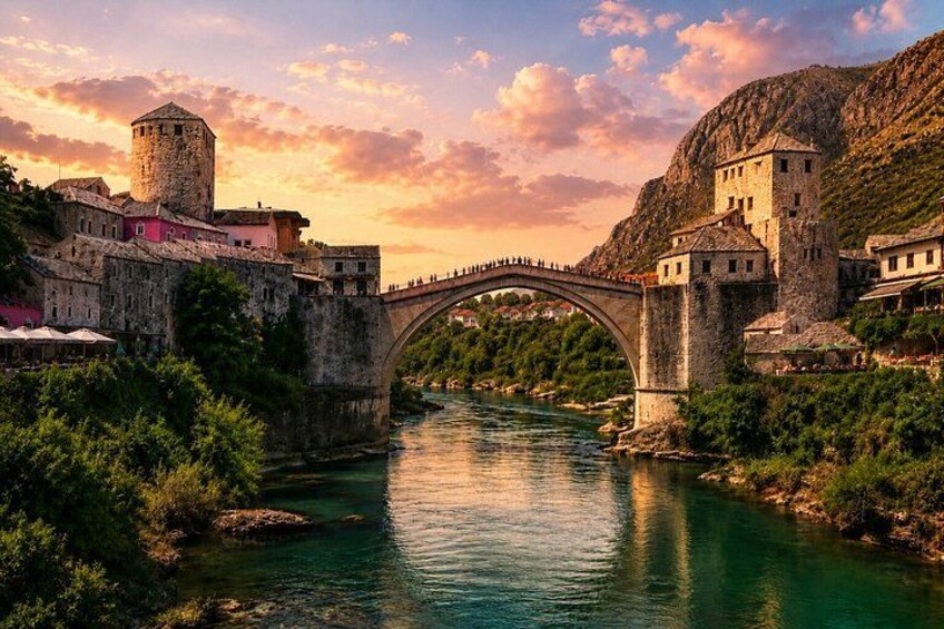 Un puente de piedra sobre un río, edificios históricos y un telón de fondo montañoso. 4
