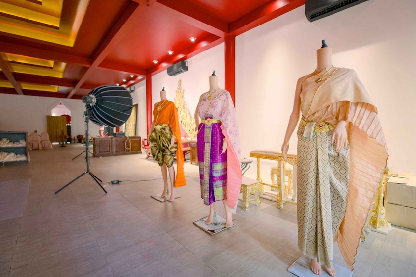 Mannequins dressed in traditional attire, a studio setting with a red ceiling, and a large softbox light. 3