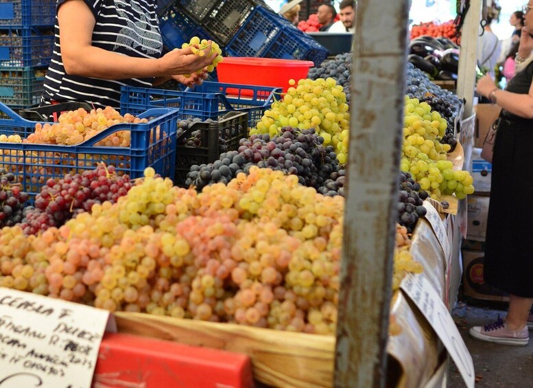 A market stall with various types of grapes displayed in baskets and crates. 1