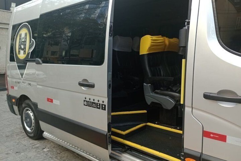 A white van with a yellow seat cover, a logo on the side, and a step leading into the vehicle. 3