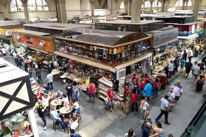A busy indoor market with various stalls and people shopping. 4