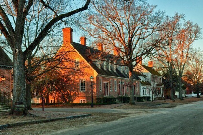 A residential street lined with brick houses, trees, and a clear sky. 1