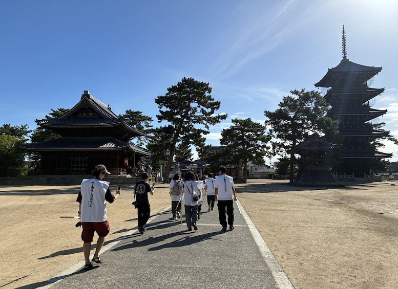 A group of people walking towards a traditional Japanese pagoda and a temple. 1