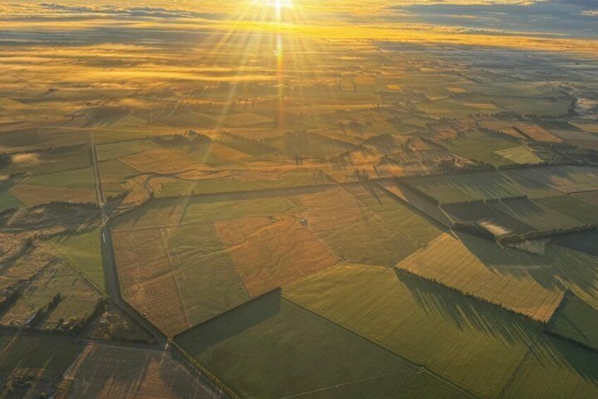 An aerial view of farmland with distinct crop patterns and a clear sky. 4