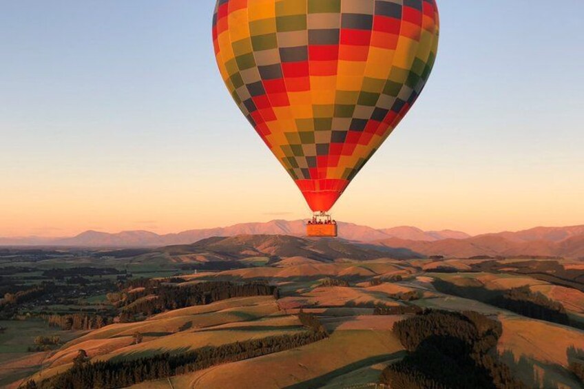 A hot air balloon over a hilly landscape at sunset. 2