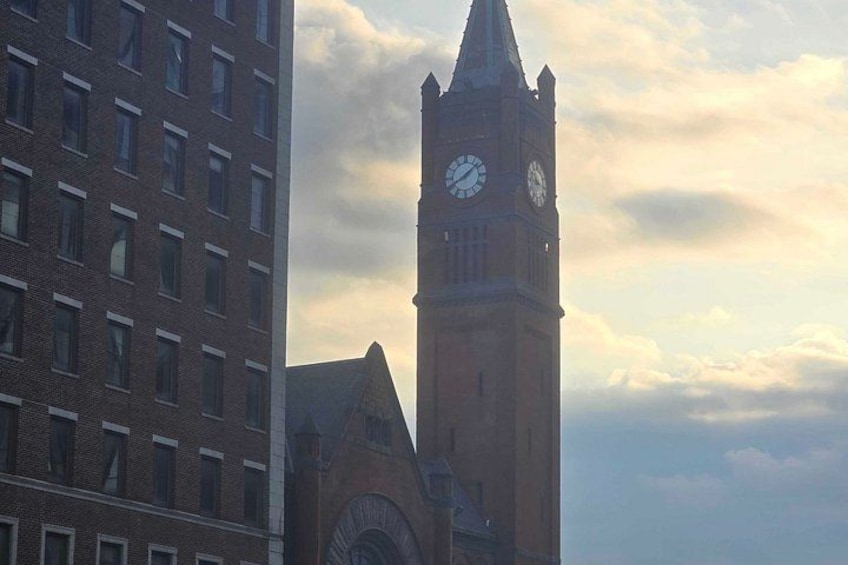 A clock tower with a clock face, a brick building, and a partly cloudy sky. 3