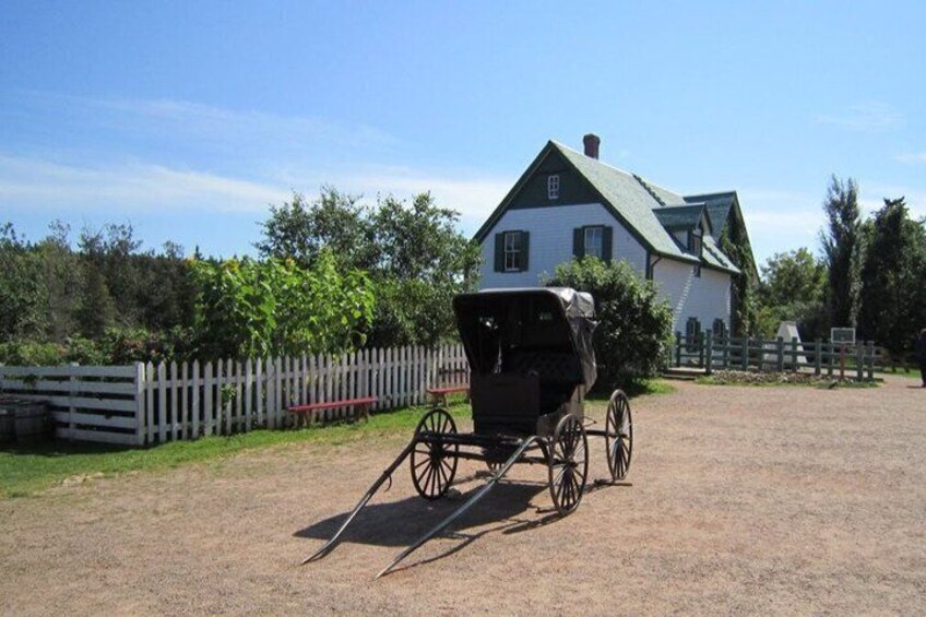 A white house with a green roof, a wooden fence, and a horse-drawn carriage. 2