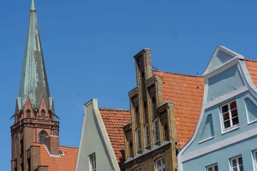 A church with a tall spire and adjacent colorful buildings with red-tiled roofs. 4