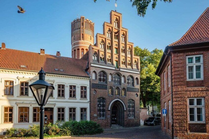 A historic building with a tower, a white building with arched windows, and a street lamp. 2