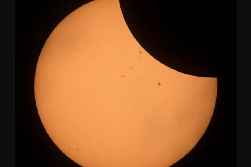 A crescent moon partially obscuring a bright orange sun. 3