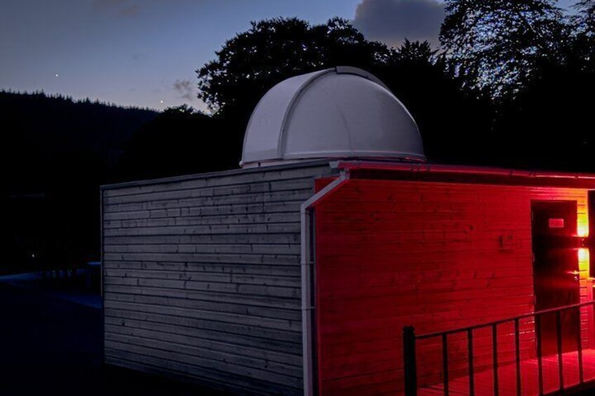 A red and white building with a dome structure, surrounded by trees and a dark sky. 2